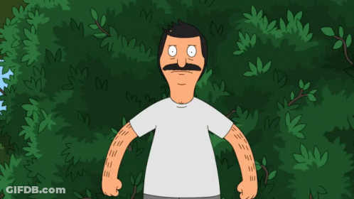 A Man With A Mustache Is Standing In Front Of Trees GIF