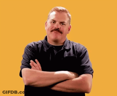 A Man With A Mustache Is Standing With His Arms Crossed In Front Of A Yellow Background GIF