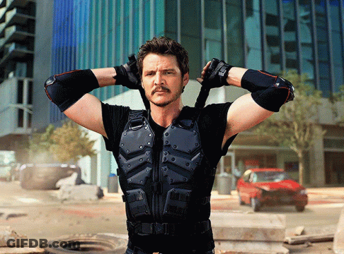 A Man With A Mustache Is Standing With His Hands Behind His Head In Front Of A Building GIF