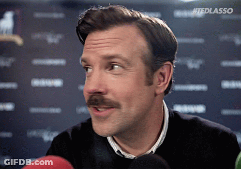 A Man With A Mustache Is Talking Into A Microphone With #Tedlasso Written On The Bottom Right GIF