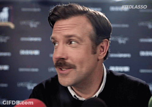 A Man With A Mustache Is Talking Into A Microphone With The Hashtag #Tedlasso On The Bottom GIF