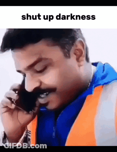 A Man With A Mustache Is Talking On A Cell Phone With The Words Shut Up Darkness Above Him GIF