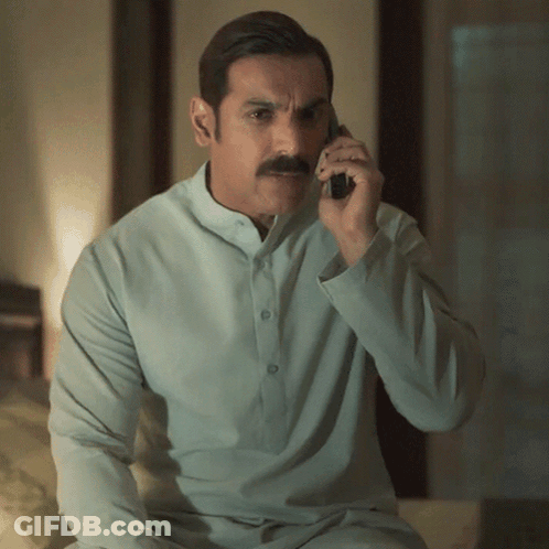 A Man With A Mustache Is Talking On A Cellphone GIF