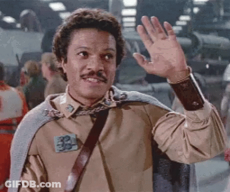 A Man With A Mustache Is Waving His Hand In Front Of A Crowd Of People . GIF