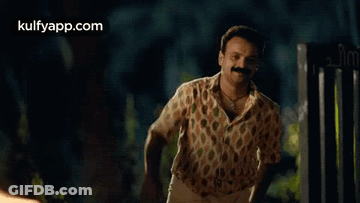 Man With Mustache Waving In Front Of Gate GIF