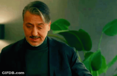 A Man With A Mustache Is Wearing A Black Turtleneck Sweater And A Black Jacket . GIF