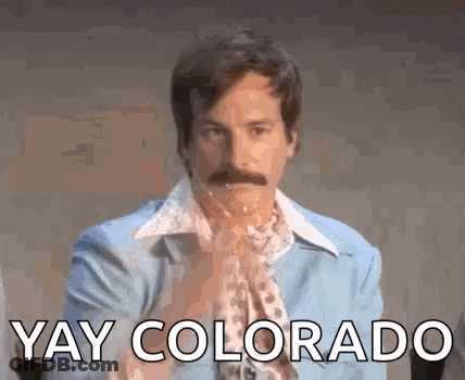 A Man With A Mustache Is Wearing A Blue Suit And A Scarf And Says `` Yay Colorado '' . GIF