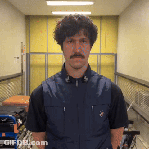 A Man With A Mustache Is Wearing A Blue Vest And Black Shirt GIF