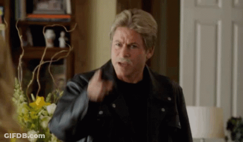 A Man With A Mustache Is Wearing A Leather Jacket And A Black Shirt . GIF