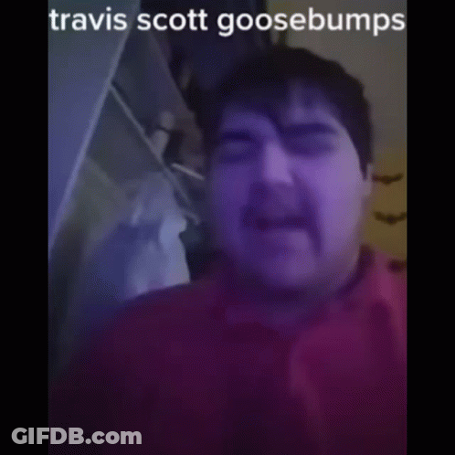 A Man With A Mustache Is Wearing A Red Shirt And Has The Name Travis Scott Goosebumps On His Face GIF
