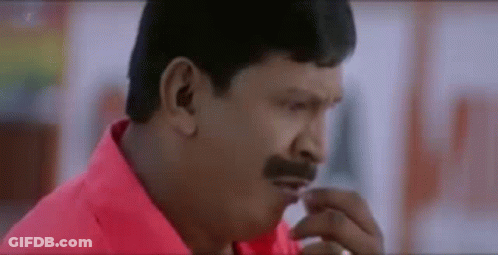 A Man With A Mustache Is Wearing A Red Shirt And Looking At Something . GIF