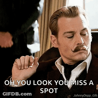 A Man With A Mustache Is Wearing A Suit And Tie And Says Oh You Look You Miss A Spot . GIF