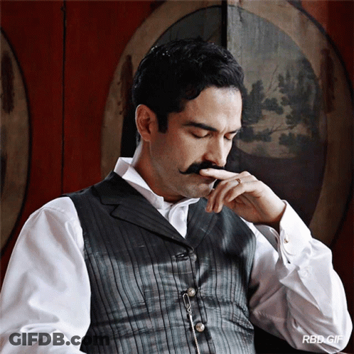 A Man With A Mustache Is Wearing A White Shirt And A Grey Vest GIF