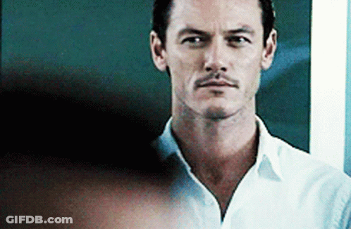 A Man With A Mustache Is Wearing A White Shirt And Looking At The Camera With A Serious Look On His Face . GIF