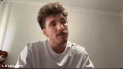 A Man With A Mustache Is Wearing A White T-Shirt And Making A Funny Face . GIF
