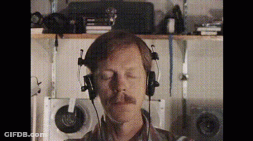 A Man With A Mustache Is Wearing Headphones With His Eyes Closed GIF