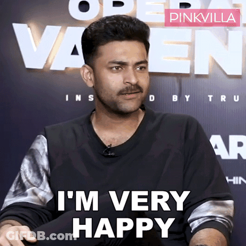 A Man With A Mustache Says I 'M Very Happy In Front Of A Pinkvilla Sign GIF