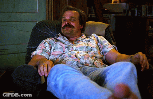 A Man With A Mustache Sits In A Chair With His Feet Up GIF