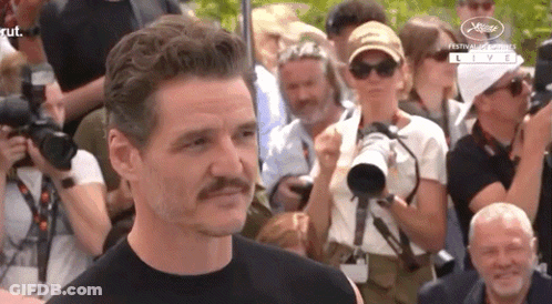 A Man With A Mustache Stands In Front Of A Crowd Of People . GIF