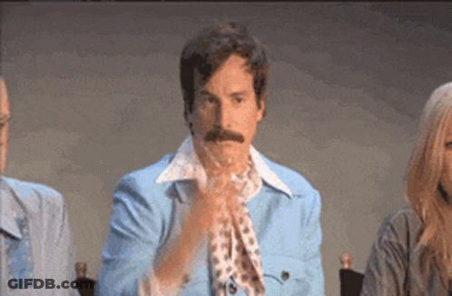 A Man With A Mustache Wearing A Blue Jacket And Scarf Is Clapping His Hands GIF