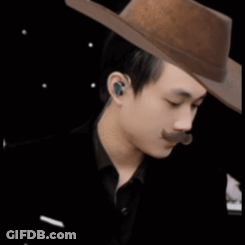 A Man With A Mustache Wearing A Cowboy Hat And Ear Buds GIF