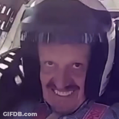 A Man With A Mustache Wearing A Helmet Is Smiling . GIF
