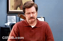 A Man With A Mustache Wearing A Red Shirt Is Sitting At A Table GIF