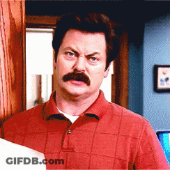 A Man With A Mustache Wearing A Red Shirt Looks At The Camera GIF