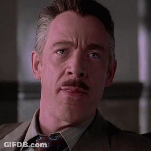 A Man With A Mustache Wearing A Suit And Tie Is Looking At The Camera GIF