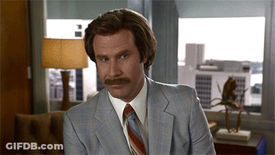 A Man With A Mustache Wearing A Suit And Tie Is Sitting In Front Of A Window GIF