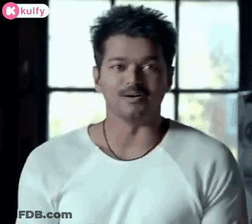 A Man With A Mustache Wearing A White Shirt Is Standing In Front Of A Window . GIF