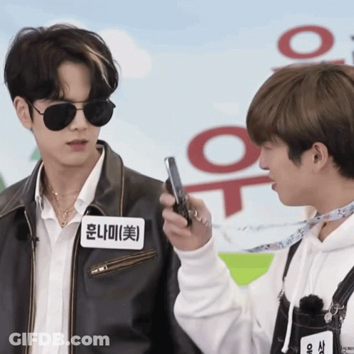A Man With A Name Tag That Says ' Hong Na Mi ' On It Holds A Cell Phone GIF