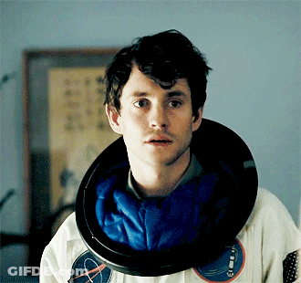 A Man With A Nasa Helmet Around His Neck Looks At The Camera GIF