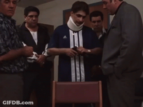 A Man With A Neck Brace Is Surrounded By Men GIF