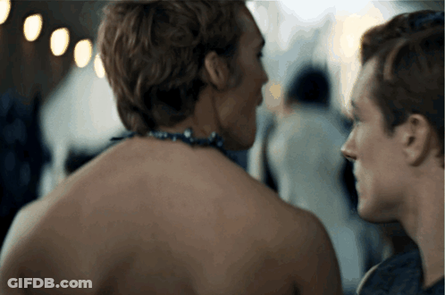 A Man With A Necklace Around His Neck Is Looking At Another Man GIF