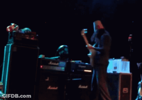 A Man With A Paper Bag On His Head Is Playing A Guitar In Front Of A Marshall Amplifier GIF