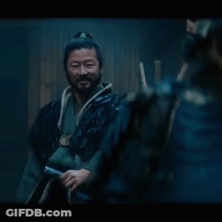 A Man With A Ponytail And A Beard Is Wearing A Black Coat GIF