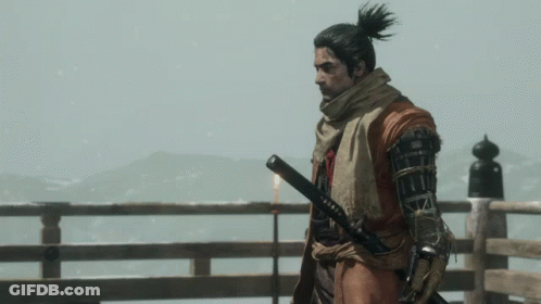 A Man With A Ponytail Is Holding A Sword In His Right Hand GIF