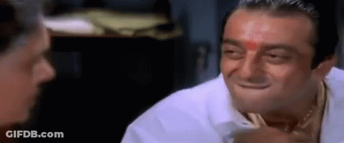 A Man With A Red Dot On His Forehead Is Smiling While Talking To Another Man . GIF