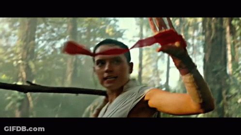 A Man With A Red Headband Is Holding A Stick In The Woods GIF