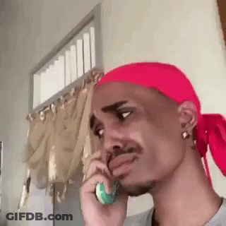 A Man With A Red Headband Is Talking On A Cell Phone . GIF