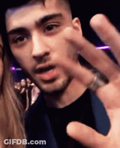 A Man With A Ring On His Finger Is Giving A Peace Sign To A Woman . GIF