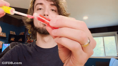 A Man With A Ring On His Finger Is Holding A Lollipop In His Hand GIF