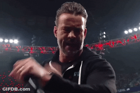 A Man With A Ring On His Finger Is Holding A Microphone And Making A Funny Face GIF