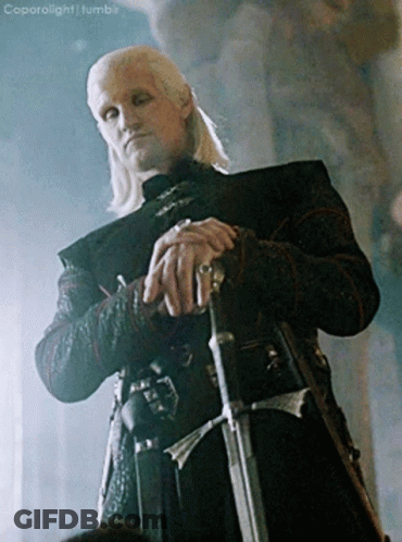 A Man With A Ring On His Finger Is Holding A Sword In His Hand GIF