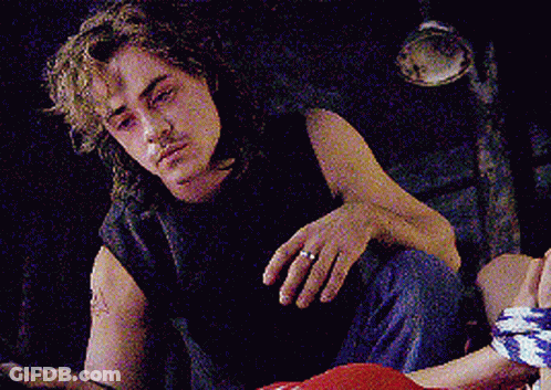 A Man With A Ring On His Finger Is Sitting On The Floor Looking At The Camera . GIF