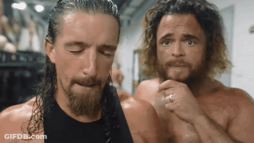A Man With A Ring On His Finger Is Standing Next To Another Man With Long Hair GIF