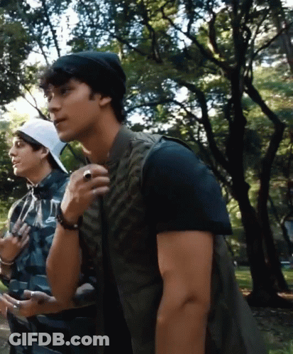 A Man With A Ring On His Finger Stands Next To Another Man In A Plaid Shirt GIF