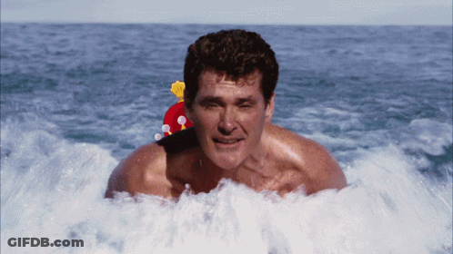 A Man With A Santa Hat On His Head Is Swimming In The Ocean GIF