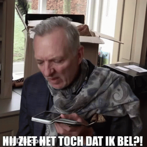 A Man With A Scarf Around His Neck Is Looking At A Cell Phone And The Caption Says Hij Ziet Het Toch Dat Ik Bel GIF